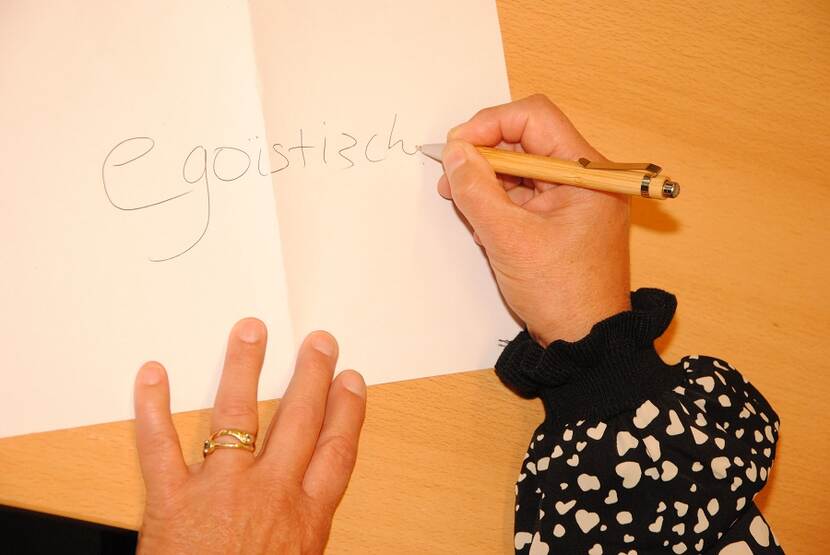 Vrouw schrijft 'egoistisch' op papier.